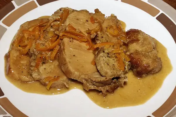 Tranches de roti de porc à l'orange, nappées d'une sauce onctueuse et garnies de zestes d'orange. Un plat savoureux et parfumé.