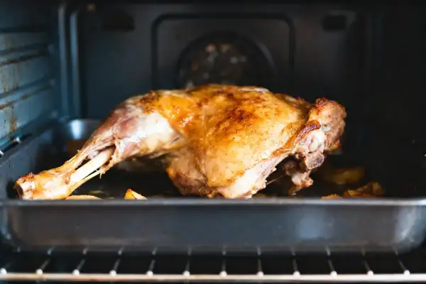Gigot d'agneau doré, prêt pour la cuisson au four. La peau croustillante promet un délice.