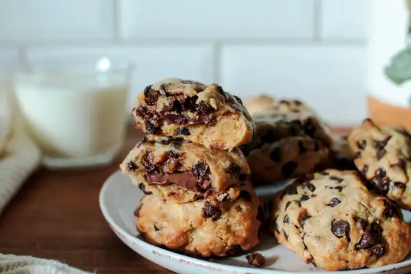 Délicieux cookies aux pépites de chocolat, parfaits pour une recette de cookies moelleux et gonflés. Un verre de lait est en arrière-plan.