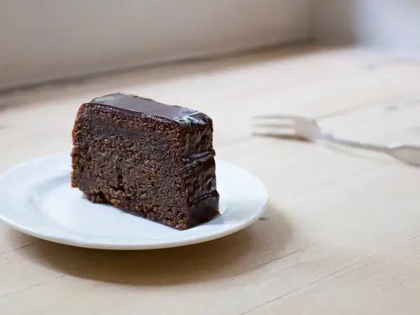 Tranche de fondant au chocolat Laurent Mariotte, nappée d'un glaçage brillant, sur une assiette blanche. Une fourchette est posée à côté.