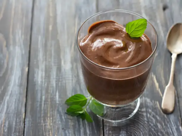Crème au chocolat onctueuse, décorée d'une feuille de menthe, comme celle de Laurent Mariotte. Une cuillère argentée est à côté.