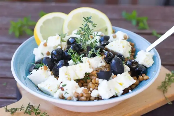 Salade de lentilles, feta, olives noires et citron, garnie de thym frais. Un délice méditerranéen.