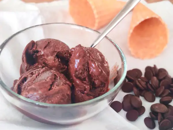 Un bol de semifreddo chocolat, avec des pépites de chocolat et des cornets à glace en arrière-plan.
